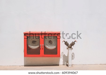 fire hydrant and red fire hose cabinet on white cement wall

