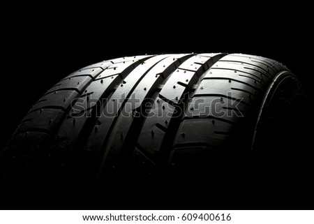 Studio shot of brand new car tire isolated on black background.