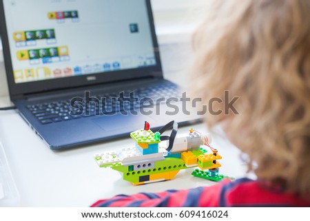 boy in robotics school makes robot, managed from the constructor, boy programming robot,  pupils in science lesson studying robotics, education, science and people concept, children, technology Royalty-Free Stock Photo #609416024