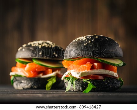 Delicious burgers of black dough with red fish on a beautiful slate board
