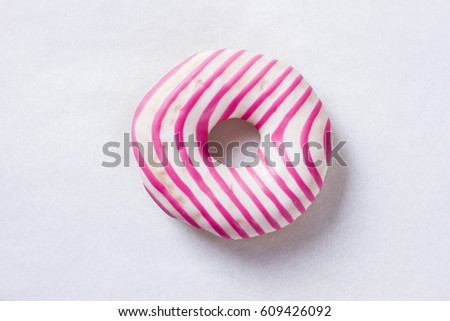 Donut with white icing and pink stripes isolated on white