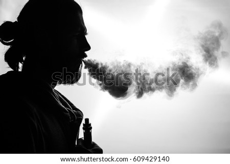 Silhouette of a bearded guy who smokes an electronic cigarette