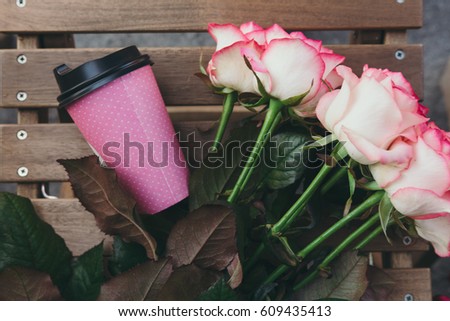  Take away coffee and  bouquet of pink roses on wooden background. Street coffee. Top view