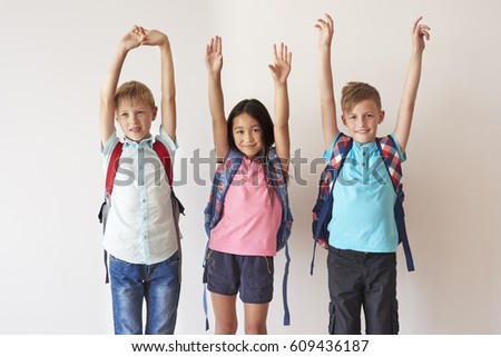 Three happy kids raising hands
