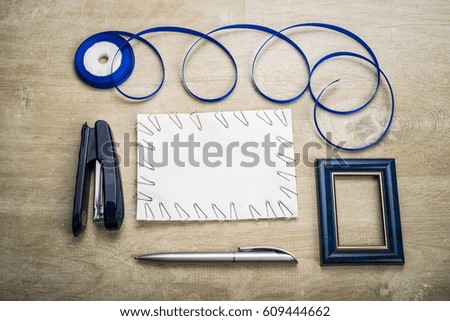 a sheet of paper stapler staples blue ribbon and handle