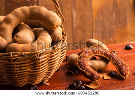 Sweet ripe tamarinds and seeds in the basket on rustic wooden table with wooden background. Copy space.