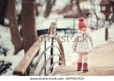 Little girl with an owl in the forest in winter
