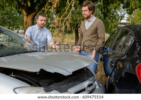Two men arguing after a car accident on the road Royalty-Free Stock Photo #609475514
