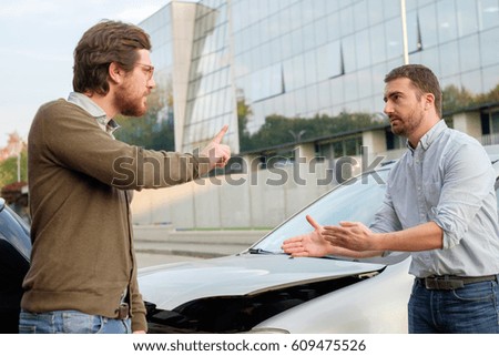 Two men arguing after a car accident on the road Royalty-Free Stock Photo #609475526