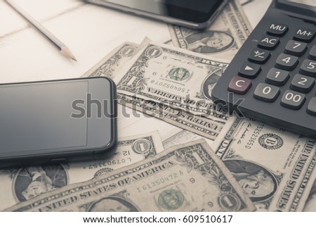 Calculator with american dollars on the wooden table background, finance concept, pencil, phone