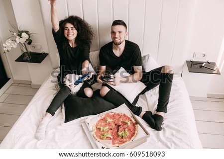 Girl wins playing with man on PS on bed Royalty-Free Stock Photo #609518093