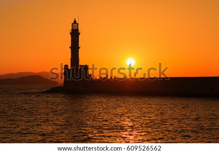 view of the lighthouse in the sea in Chania, Crete, Greece. Silhouettes against the setting sun.
