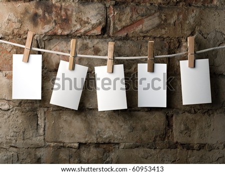 five photo paper attach to rope with clothes pins on brick background