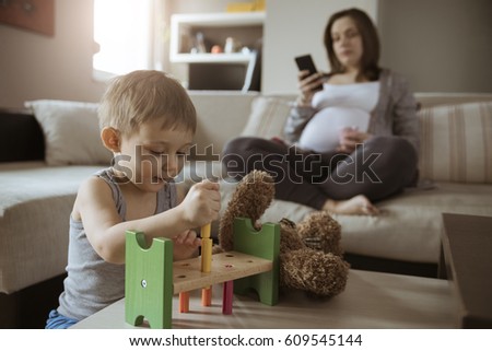Little Cute Son Playing While His Pregnant Mom Is On The Phone