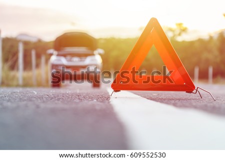 Red emergency stop sign and broken silver SUV car on the road