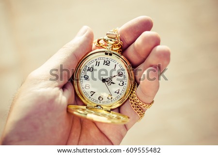 Golden pocket watch in hand close up. Royalty-Free Stock Photo #609555482