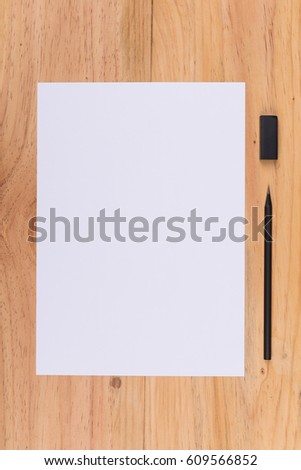 Top view of white paper, pencil and eraser on wooden table