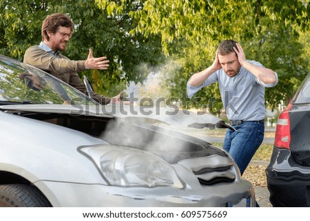 Two men arguing after a car accident on the road Royalty-Free Stock Photo #609575669