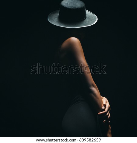 dark skinned woman on a black background with a fashionable hat on his head