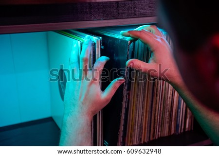 Close up man's hands browsing through vinyl records collection. Music background. Selective focus