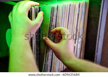 Close up man's hands browsing through vinyl records collection. Music background. Selective focus