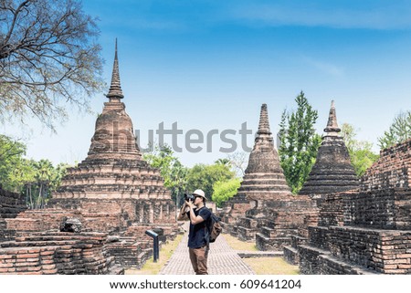 man with backpack taking a photo at Sukhothai  Historical Park,public place in Thailand