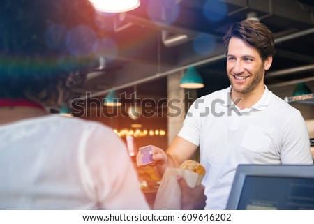 Graphic image of flare against happy customer paying by credit card for bread