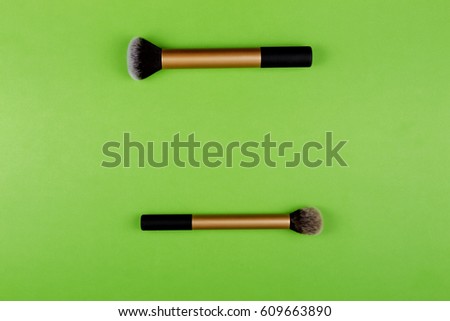 Two make up brushes on greenery background. Top view.