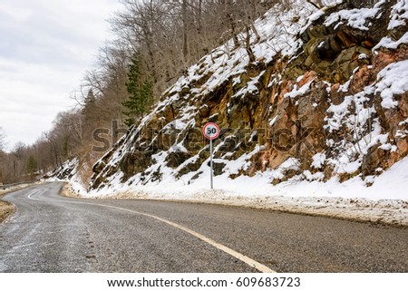 European speed limit traffic sign on winter road in mountains