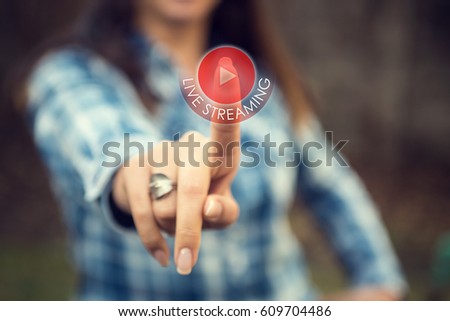 Woman pressing live streaming play button on digital display. Person tracking live event on the internet and touching livestream web button on touch screen. Royalty-Free Stock Photo #609704486