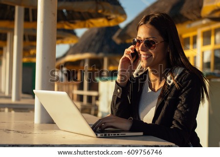 Smart girl talking via phone on the beach