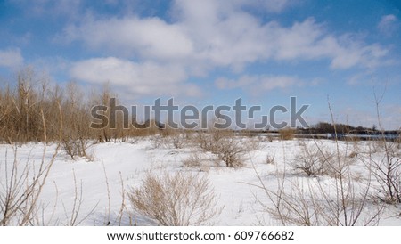 River between snowy beach and blue sky with clouds