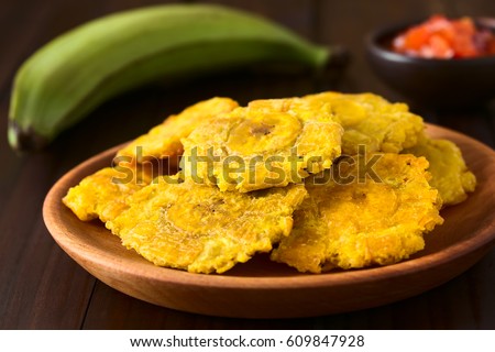 Patacon or toston, fried and flattened pieces of green plantain, traditional snack or accompaniment in the Caribbean, photographed with natural light (Selective Focus on the front of the top patacon)  Royalty-Free Stock Photo #609847928