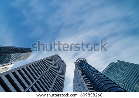 Business buildings skyline looking up with blue sky background. High-rise skyscraper, modern architecture.