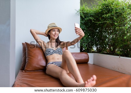 Woman taking selfie by mobile phone with bikini