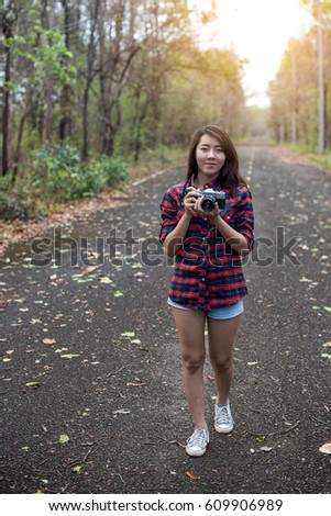 Beautiful woman with retro camera on the street in the forest alone.