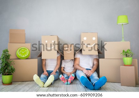 Happy family playing into new home. Father, mother and child having fun together. Moving house day and "think outside the box" concept