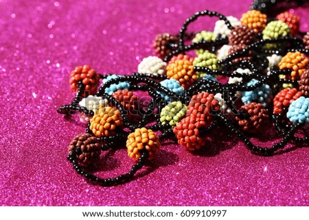 Colorful beads closeup isolated on pink glitter background