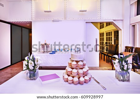 well decorated kitchen with food on table.  white cloth covering the table, cupcake and bouquet on table.