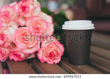  Take away coffee and  bouquet of pink roses on wooden background. Street coffee