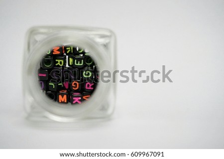 Small alphabet blocks in a glass bottle isolated on white background