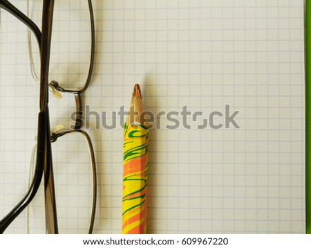 Paper and color pencil and part of glasses
