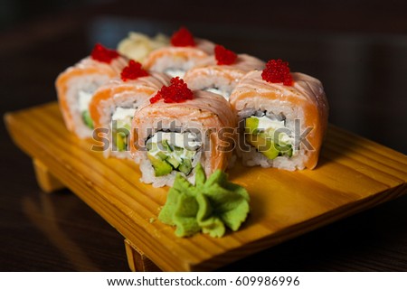 Close up of tasty fresh sushi rolls with fish and rice on wood background. Sushi rolls served on a wooden plate in a restaurant