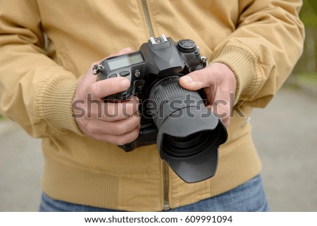 man photographer holding his photo camera, outdoor