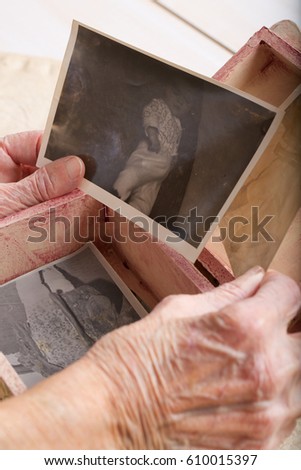 Old woman opens a wooden made box with her photos