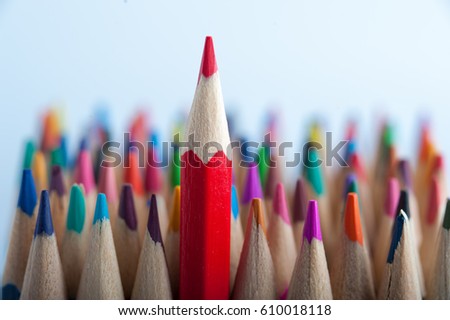 Red pencil on the background of colorful crayons