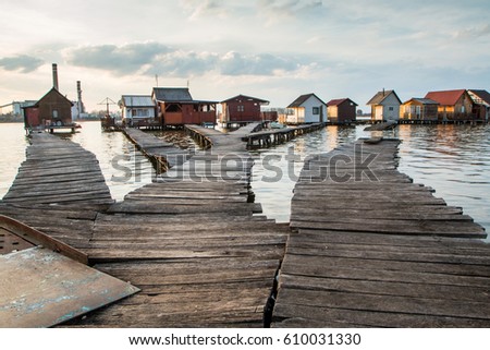 A picture taken by the Bokod lake in Hungary during the evening. The "floating" houses on pillars can be seen. The sun is going down behind the haze. A nice, calm and lonely place. 