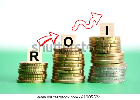 Return on investment analysis with ROI text on wooden cubes on top of upward stacked coins