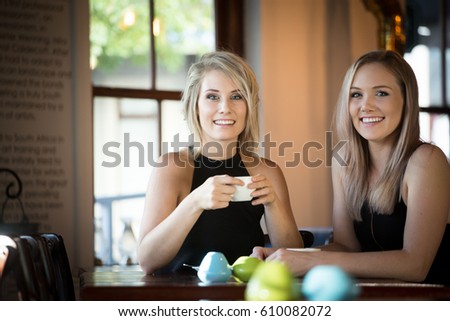 Close up image of two young girlfriends enjoying a cup of coffee in a trendy coffee shop