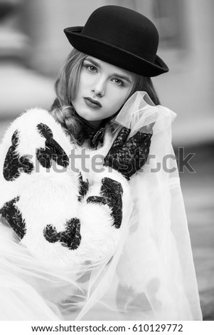 Woman in black and white clothes. Stylish retro urban girl trendy new age look. Accessories hat and Gloves. Portrait of fashion model posing in city stree.